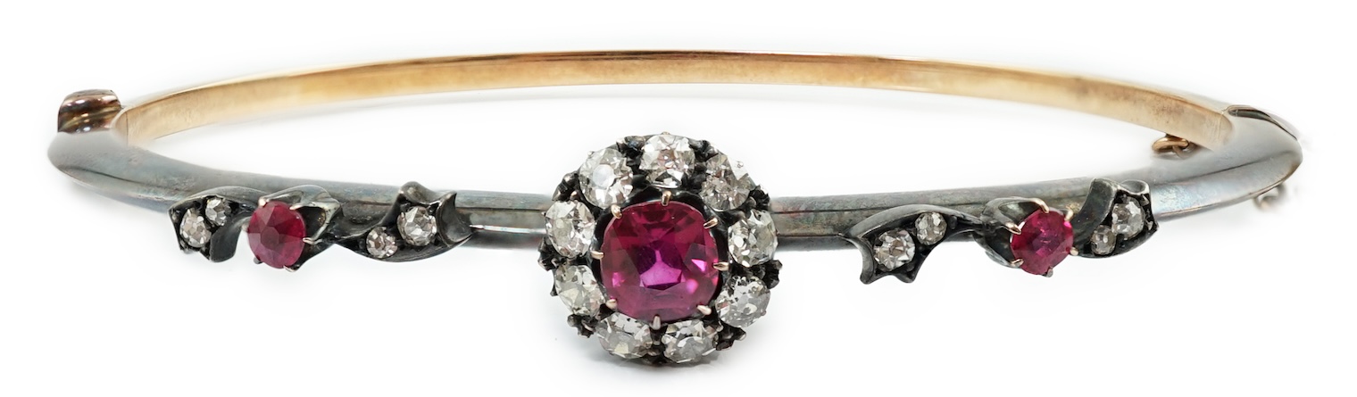 A late Victorian gold and silver, ruby and diamond cluster set hinged bangle